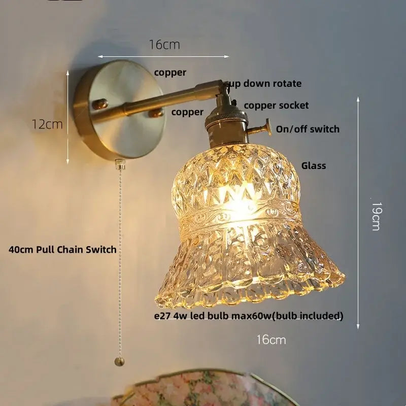 Antique brass-finished wall light fixture with faceted clear glass bell-shaped shade and amber flower crystal design