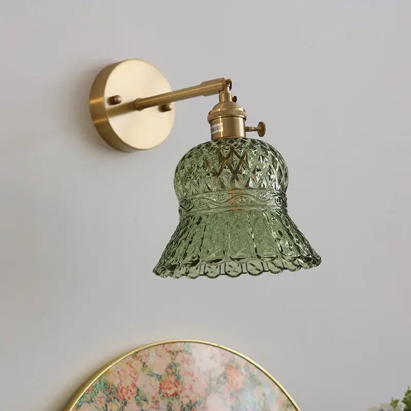 Vintage-style wall light fixture with green textured glass shade and brass-finished metal arms for bedroom use