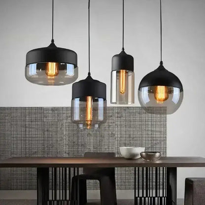 Set of four modern pendant light fixtures with black metal tops and amber smoked glass shades for dining room