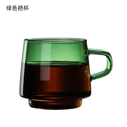 A translucent green decorbites glass coffee mug with a sturdy handle filled halfway with dark liquid for tea or juice
