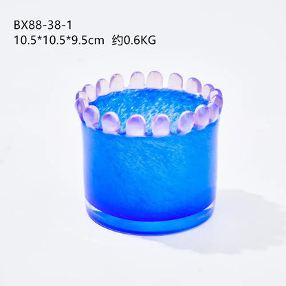 Blue glass cylinder candle holder with scalloped rim and translucent purple accents complements colored lace decor