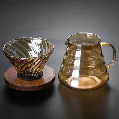 Amber-tinted glass coffee filter pot with fluted twisted design and matching carafe on wooden base for pour-over brewing