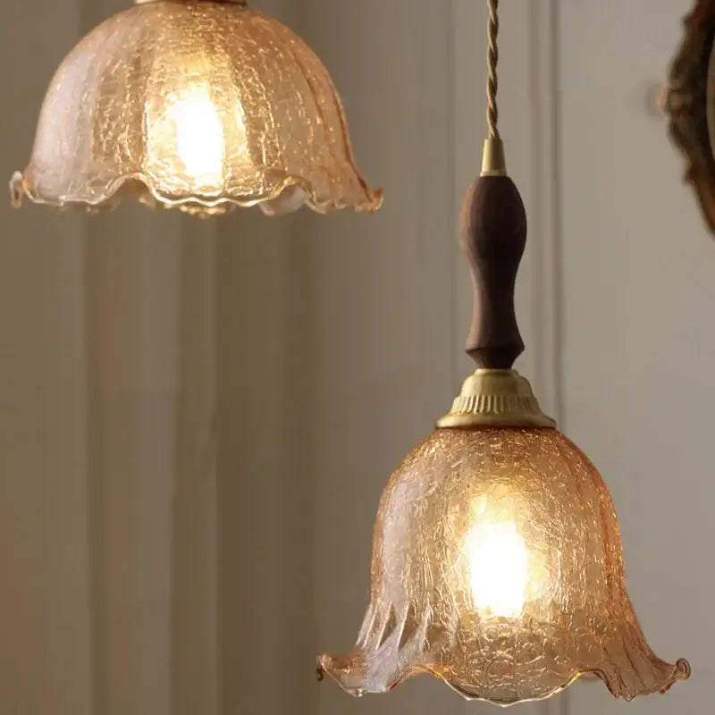 Warm amber-colored glass led pendant lamp with textured glass, walnut handle, and brass accents for kitchen lighting