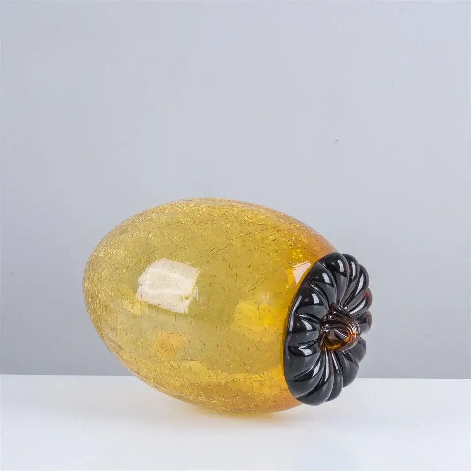 Amber and orange glass hazelnut pinecone ornament featuring a golden amber apple with a glossy black stem for living room decor