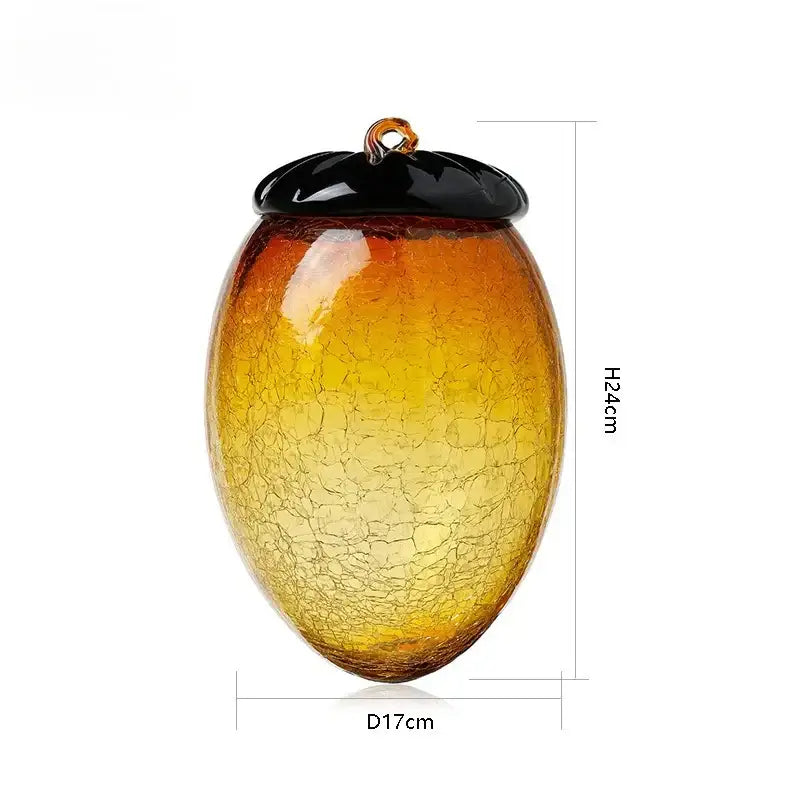 A translucent amber glass hazelnut pinecone ornament with a black lid and orange loop for living room decor