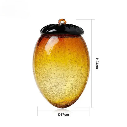 A translucent amber glass hazelnut pinecone ornament with a black lid and orange loop for living room decor