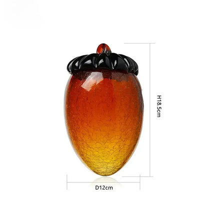 Translucent amber and orange glass hazelnut pinecone ornament with crackled texture and glossy black cap for living room decor