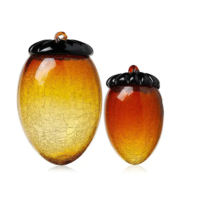 Two hand blown glass hazelnut pinecone ornaments in amber and orange with glossy black caps for living room decor
