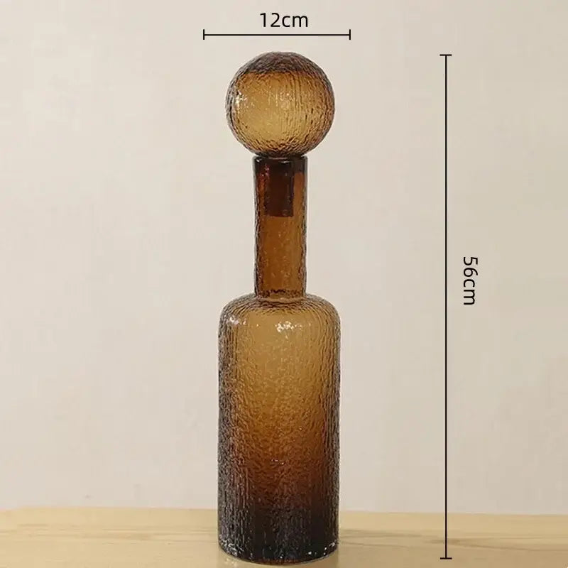 A tall amber textured decorbites clear glass decanter with a rounded stopper for living room decor