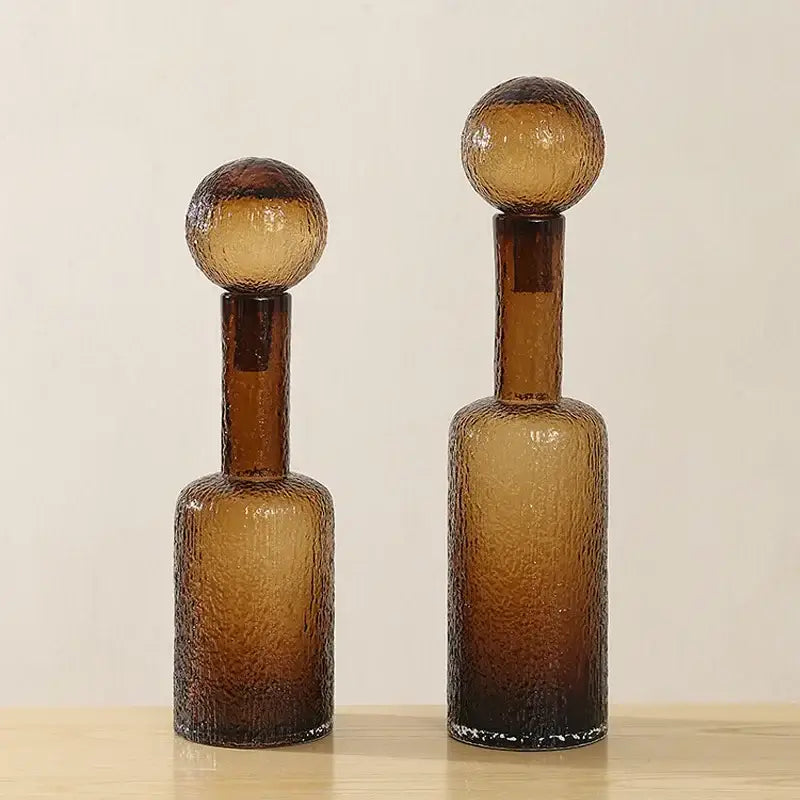 Two amber decorbites clear glass decanters with textured surfaces and spherical tops for living room decor