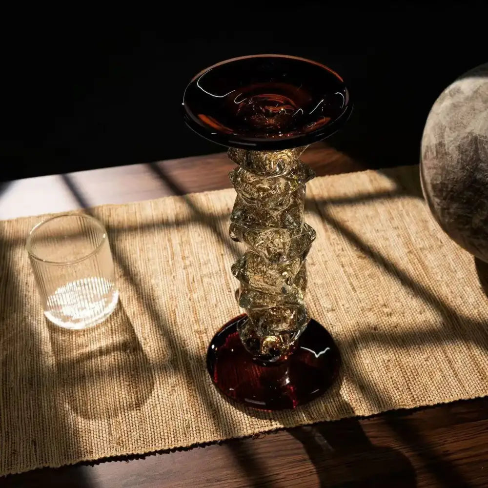 A tall glass splicing candelabrum with amber translucent segments and deep red base for dining room decor