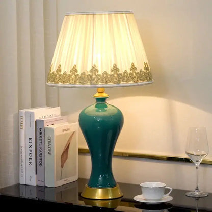 Teal ceramic table lamp with gold accents and cream pleated shade featuring ornate gold trim by decorbites american luxury