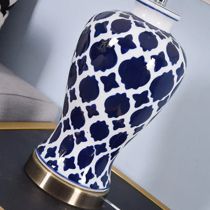Glossy white ceramic table lamp with blue floral pattern and gold-toned circular foot by decorbites blue ceramic