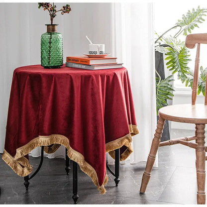 A rich burgundy table cloth with gold fringe trim made of velvet ideal for decorbites gold velvet wedding and dining room decor