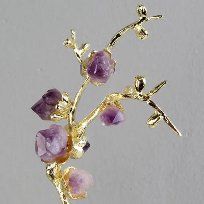 A delicate gold-toned brass tree ornament shaped like a blossoming branch with faceted purple amethyst stones
