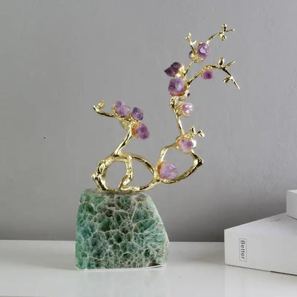 A delicate gold-toned brass tree ornament with faceted purple amethyst stones on green aventurine base
