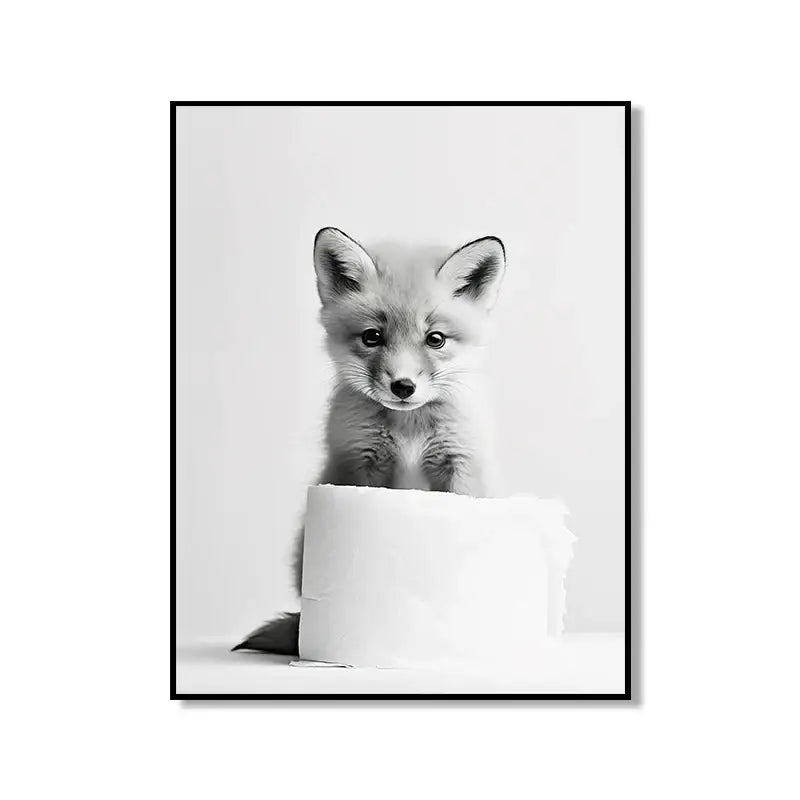 Black-and-white framed DecorBites bathroom wall art featuring a curious fox pup peeking over a toilet paper roll cute animal canvas