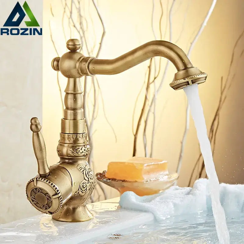 Antique brass-finished basin mixer tap with ornate floral engraving and curved swivel spout for bathroom use