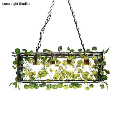 Rectangular metal island pendant in antique black with LED downlighting and artificial green leaves in wire mesh design