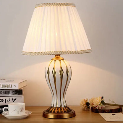 Elegant white ceramic table lamp with gold geometric accents and cream shade in antique blue ceramic style for bedroom use