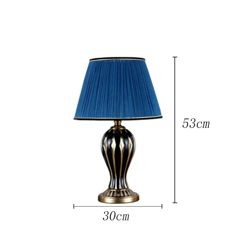 Elegant antique blue ceramic desk lamp with pleated blue shade and gold accented black striped base for bedroom use