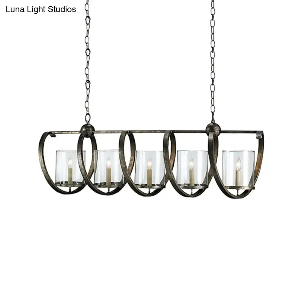 Antique brass dining room chandelier with five clear glass candle holders and lit white taper candles in bronze finish