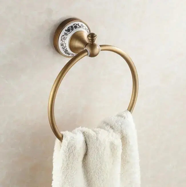 Antique brass towel ring with decorative white ceramic plate and black floral patterns from decorbites bathroom accessories set