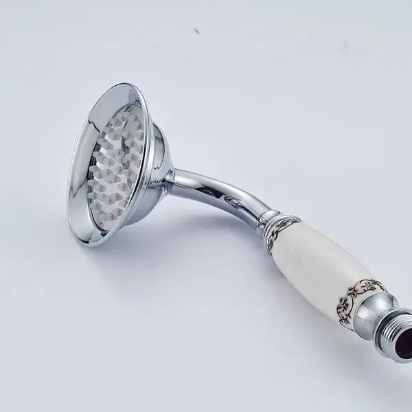 Antique brass and chrome hand shower head with chrome finish and cream ceramic handle featuring black floral patterns