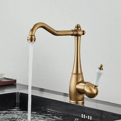 Antique brass basin waterfall faucet with white ceramic handle and elegant curved spout for kitchen use