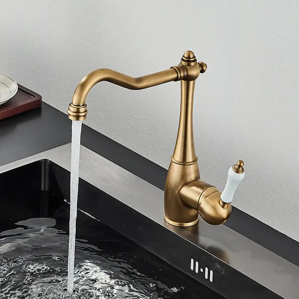 Antique brass basin waterfall faucet with white ceramic handle and elegant curved spout for kitchen use