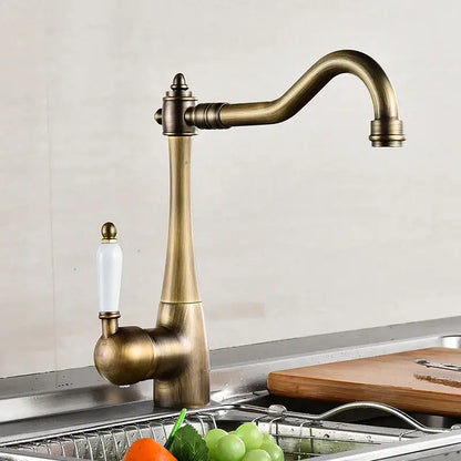 Antique brass and white ceramic kitchen faucet swivel mixer with an elegant curved spout and white ceramic handle