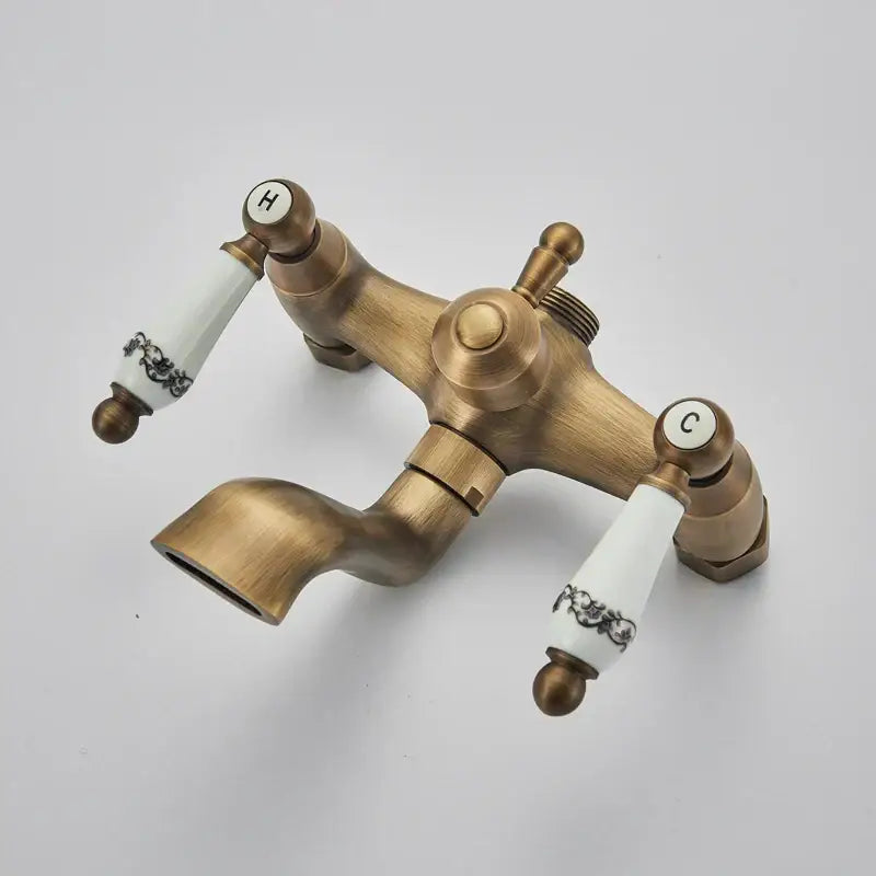 Antique brass and white ceramic shower faucet set with black floral handles labeled h and c for hot and cold use