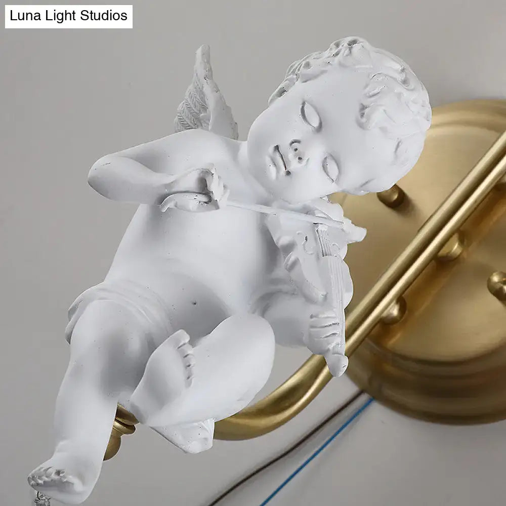 White angel figurine with delicate wings holding a violin as part of an antique brass glass sconce light for bedroom wall