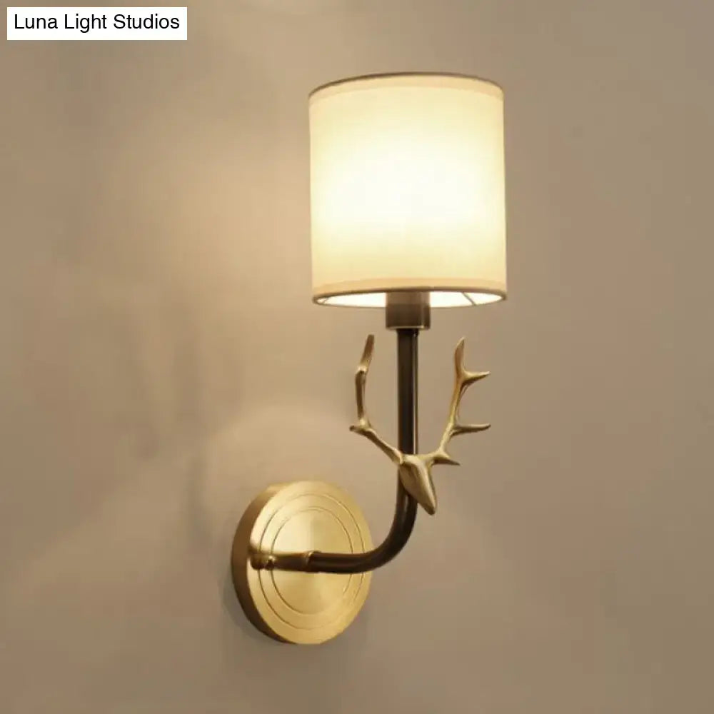 Antique brass wall sconce with gold-toned antler design and off-white fabric shade for stylish bedroom lighting