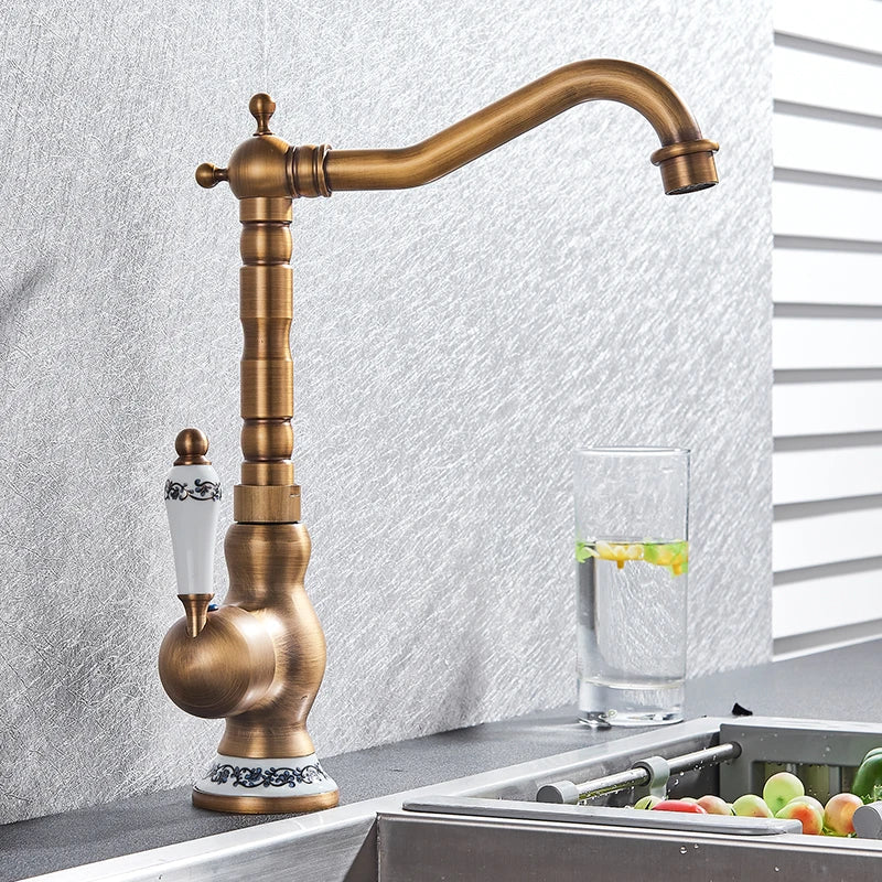 Antique brass basin faucet with white ceramic handle featuring black floral detailing and ornate base trim