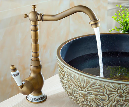 Antique brass basin faucet featuring ornate detailing with white ceramic handle accents for bathroom sinks
