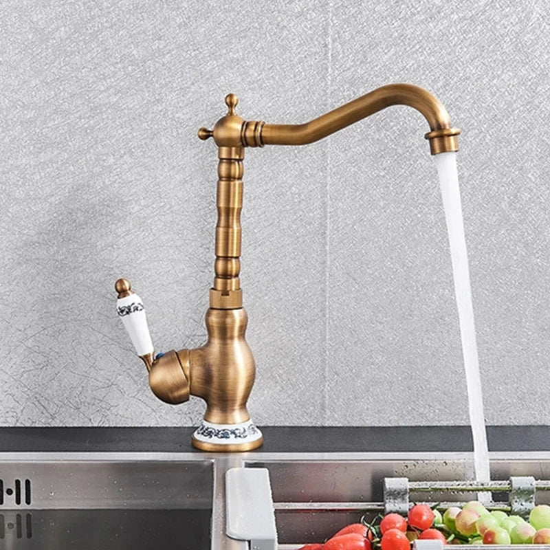 Antique brass basin faucet with a curved spout and decorative porcelain handle featuring black floral patterns