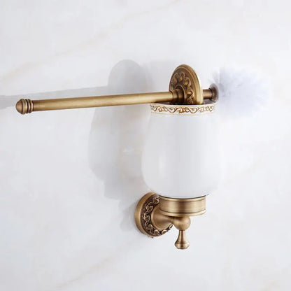 Antique brass bath hardware set featuring a white ceramic toilet brush holder with ornate floral decorbites brass antique detailing