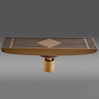 Antique brass carved rectangular floor drain cover with diamond-shaped inlay and slatted design for bathroom drainage