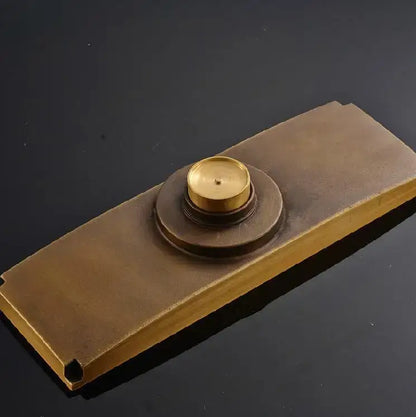 Antique brass floor drain cover with a carved floral design and a circular raised doorbell push plate center