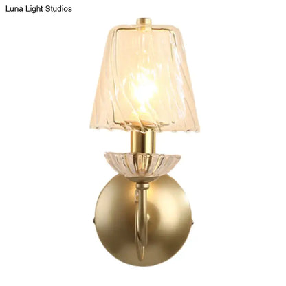 Gold-finished conical sconce light with clear twisted glass shade and crystal petal accent for bedroom lighting
