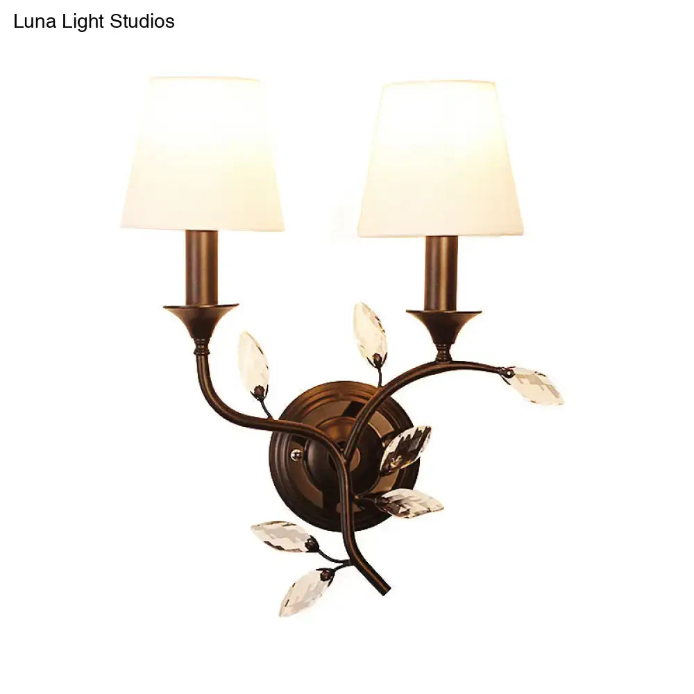 Antique brass wall mount lamp featuring bronze two-light sconce with crystal leaf accents and cream fabric shades