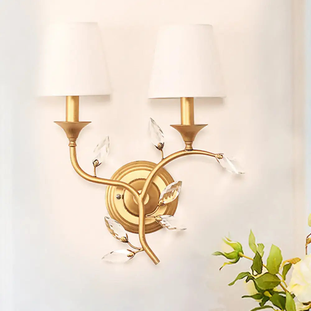Antique brass wall mount lamp with gold tone, two white lampshades, and crystal leaf accents for bedroom use