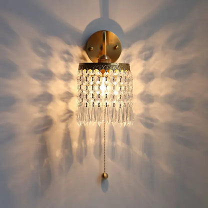 Antique brass crystal led wall sconce with gold-toned finish and cascading clear crystal droplets with pull chain