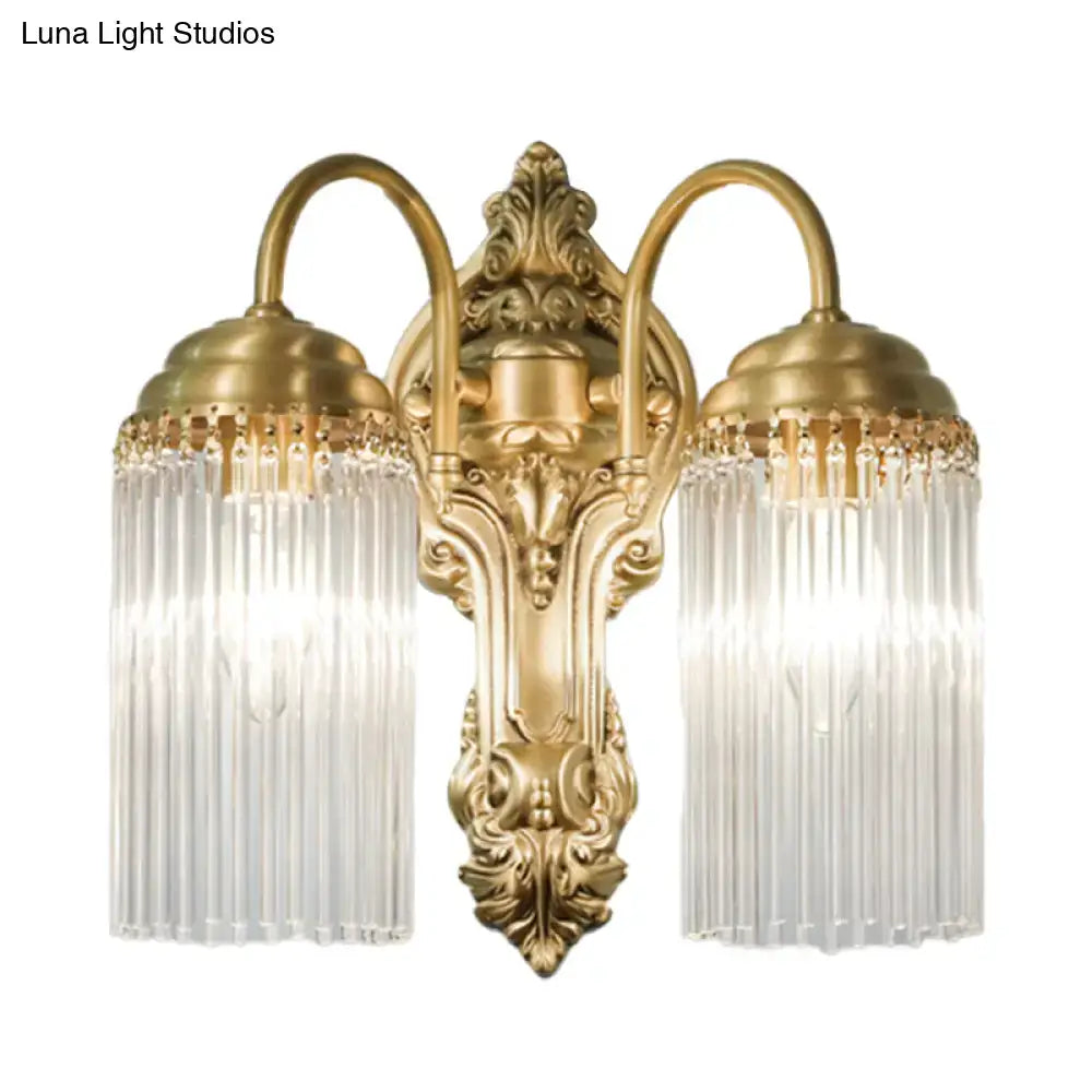 Antique brass two-light wall sconce with ornate scrollwork and vertical crystal rod prisms for corridor lighting