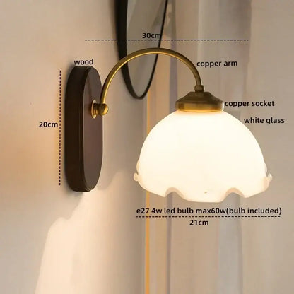 Antique brass floral frosted glass led wall light with dark wood backplate and scalloped white shade for bedroom sconce