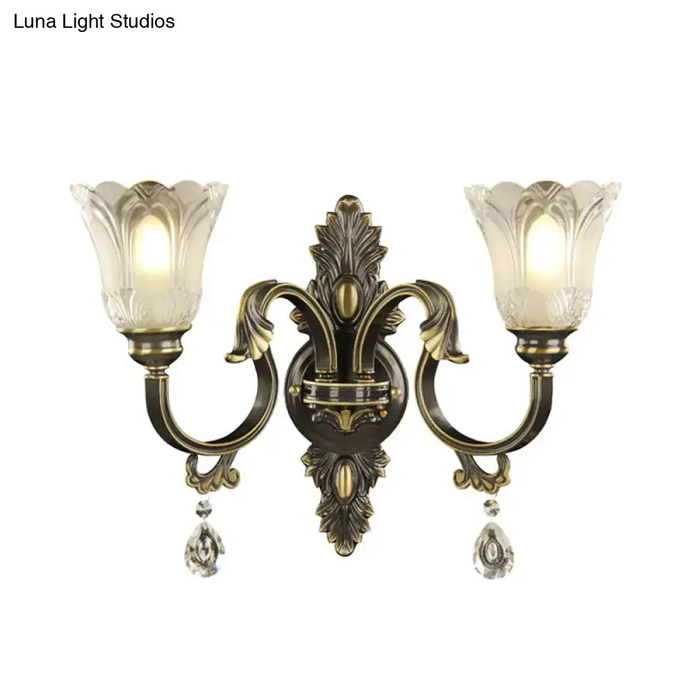 Antique brass floral wall sconce with metal base, two lights, frosted glass flower shades, and crystal pendants, inches tall