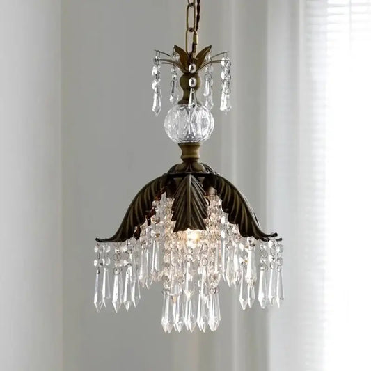 Antique brass leaf crystal pendant light featuring bronze leaf design with cascading clear prisms and faceted globe chandelier