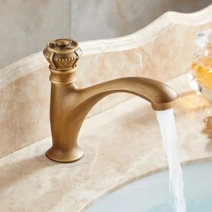 Antique brass single handle basin faucet with ornate crown-like handle and curved spout for bathroom use