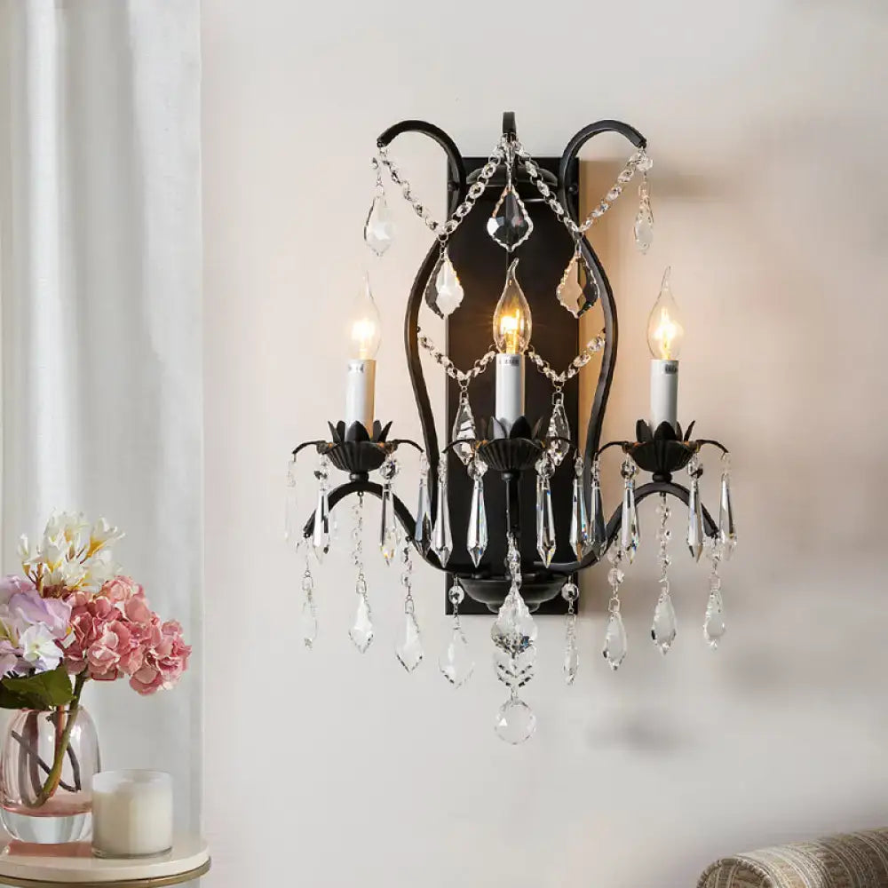 Black wrought iron candelabra wall light with three candle bulbs and crystal droplets for dining room use